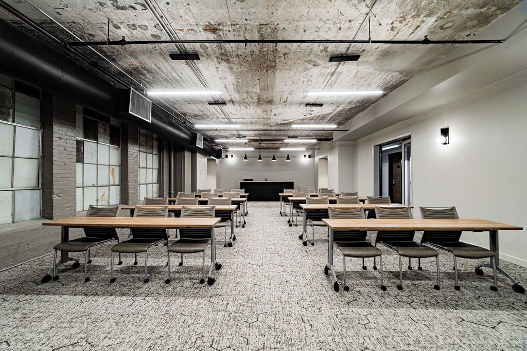 A conference room with a long table, chairs, and a carpeted floor.