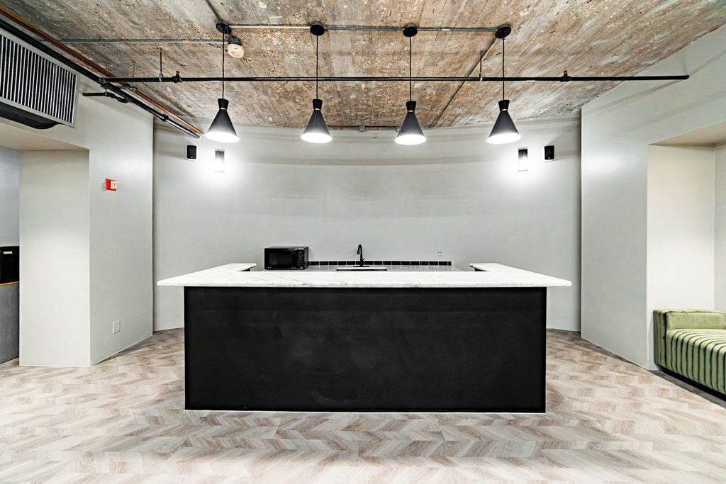 A modern kitchen with a central island, pendant lighting, and a herringbone-patterned floor.