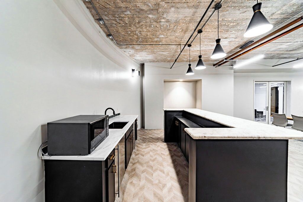 A modern kitchen with a herringbone floor, black cabinetry, and pendant lighting.
