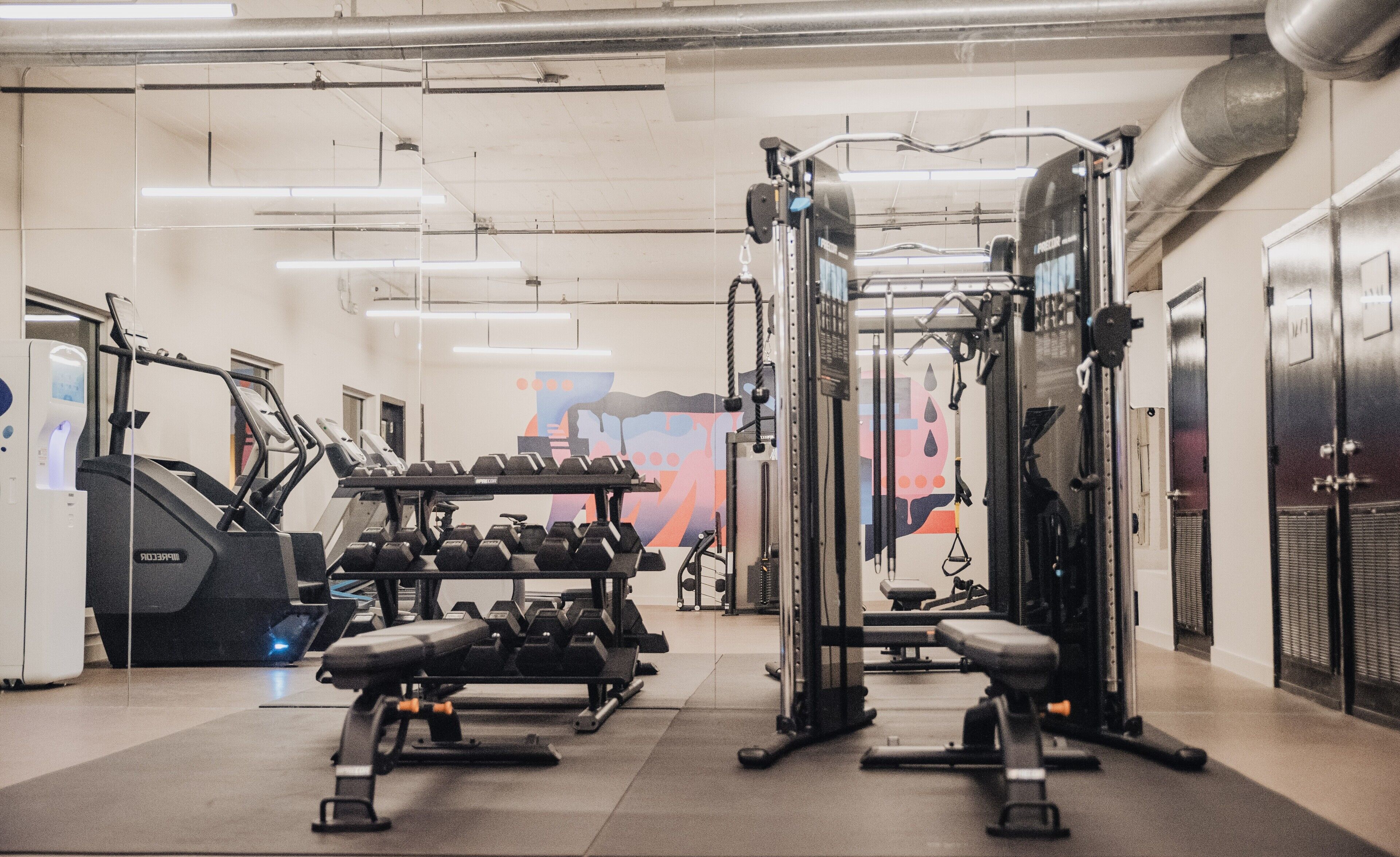 A gym with exercise equipment, benches, and dumbbells.
