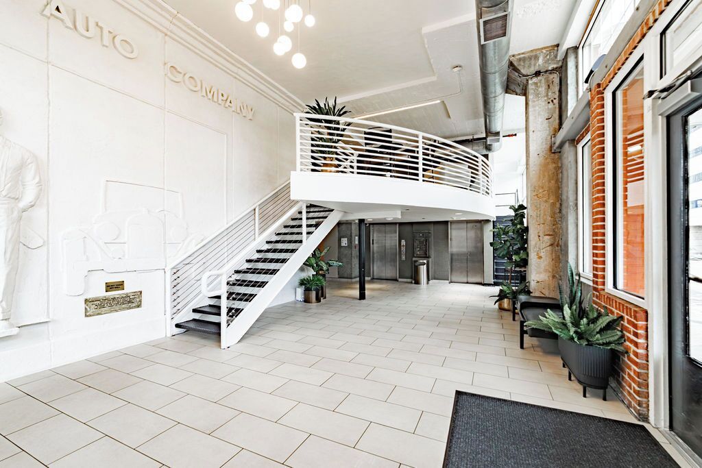 A modern interior with a white staircase, a reception desk, and a brick wall.