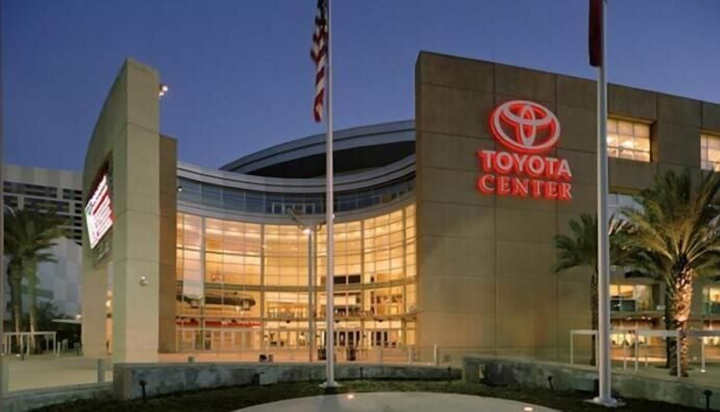 Un edificio moderno con fachada curva, grandes ventanales y un llamativo letrero del Toyota Center.
