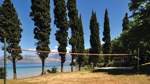 A volleyball net set up in a grassy area with a clear view of a lake and mountains in the background. - Stunning home in Postira (Postira)