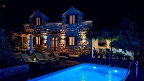 A stone building with a swimming pool, lounge chairs, and a barbecue area. - Stunning home in Postira (Postira)