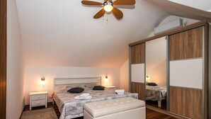 A bedroom with a bed, bedside tables, a mirror, a ceiling fan, and a wardrobe. - Stunning home in Postira (Postira)