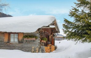 Eine rustikale Holzhütte mit schneebedecktem Dach, Holzläden und einem Steinfundament.