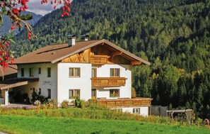 A two-story house with a sloped roof, wooden balcony, and a garden in front. - Ferienwohnung in ruhiger Lage (Trins)