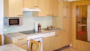 Een kleine keuken met houten kastjes, een magnetron, een spoelbak en een vaatwasser.