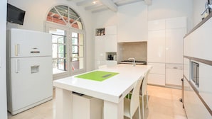 A modern kitchen with white cabinetry, a central island, and a built-in oven.