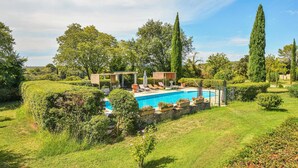A private pool area with a stone wall, lounge chairs, and a pergola.