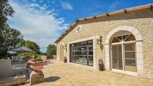 A stone building with a large glass door and windows, outdoor seating, and a decorative fountain.