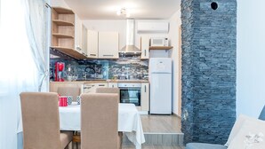 Eine kleine Küche mit Holzschränken, einer eingebauten Mikrowelle und einer Wand mit Natursteinverkleidung.