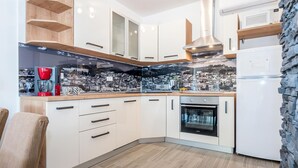 Eine moderne Küche mit weißen Schränken, einem eingebauten Backofen und einer Kaffeemaschine.