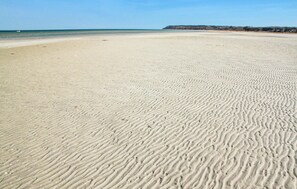 A wide sandy beach with gentle waves, a clear sky, and a distant shoreline. - 8 bedroom awesome home in Glesborg (Glesborg)