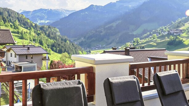 Ein Balkon mit Blick auf eine gebirgige Landschaft, einschließlich Häuser und Grünflächen.
