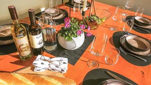 Ein gedeckter Tisch mit Weinflaschen, Gläsern, Besteck und einem Brötchen.