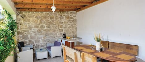 Un espacio al aire libre acogedor con pared de piedra, techo de madera y una mesa de comedor con sillas.