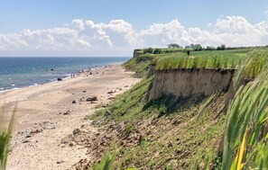 Een kustlandschap met een zandstrand, kliffen en de oceaan.
