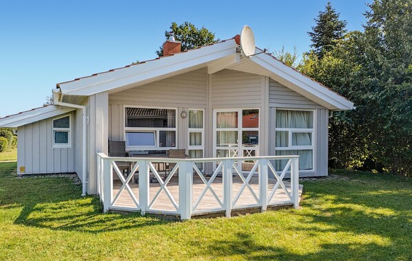 Een gelijkvloers huis met een veranda, grote ramen en een schotelantenne.
