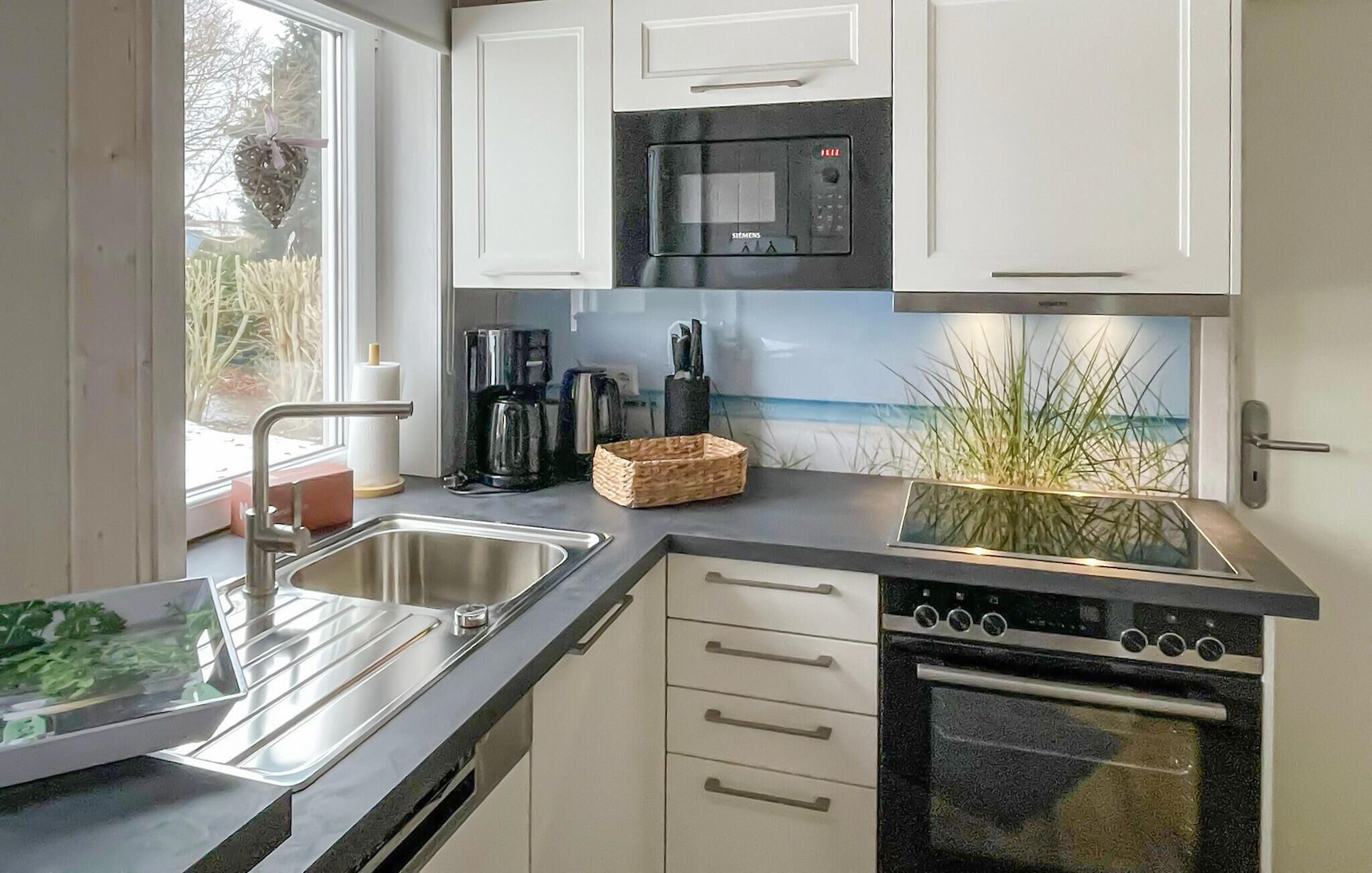 Una cucina moderna con lavello in acciaio inossidabile, una macchina per il caffè, un forno a microonde e un forno.