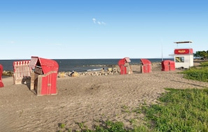 A beach with red and white striped beach chairs, a lifeguard tower, and rocky shoreline.