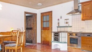 Una cucina con mobili in legno, forno a incasso e zona pranzo con tavolo e sedie in legno.