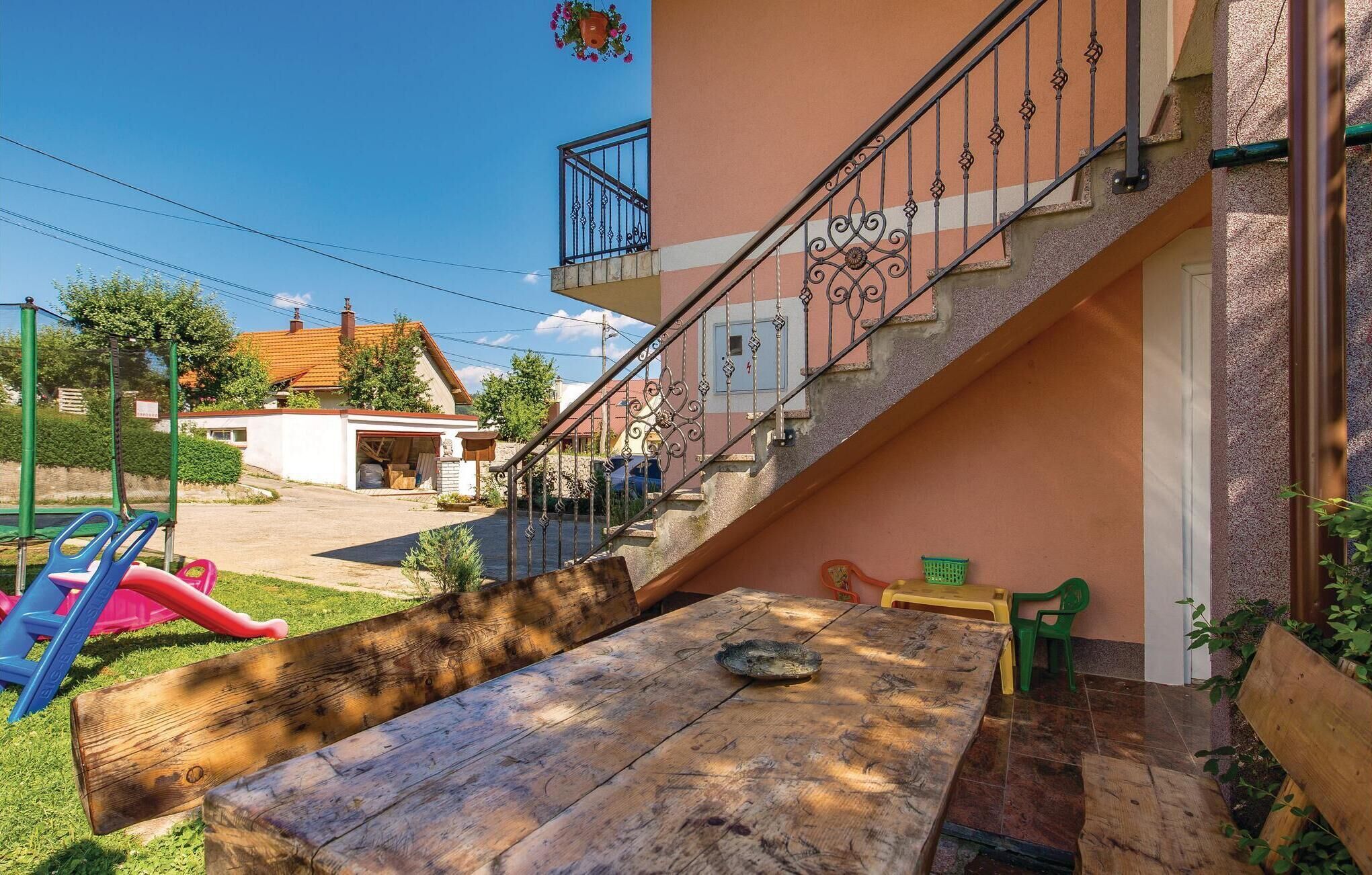 A wooden table with a bowl, a staircase with ornate railings, and a playground with a slide.