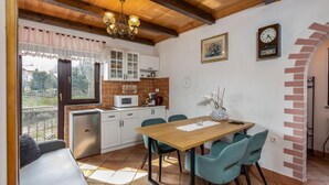 A cozy kitchen with a wooden table, teal chairs, and a view of the outdoors. - 3 bedroom nice home in Fuzine (Fuzine)