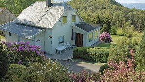 A white house with a sloped roof, a chimney, and a porch with white chairs. - Amazing home in Tau with house sea view (Tau)