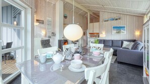 Une pièce chaleureuse et bien éclairée, avec une table à manger dressée pour le thé, un canapé et une cheminée.