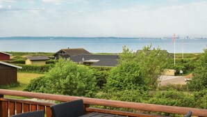Blick auf die Küste mit einer Holzterrasse, einer Flagge und einer entfernten Skyline.