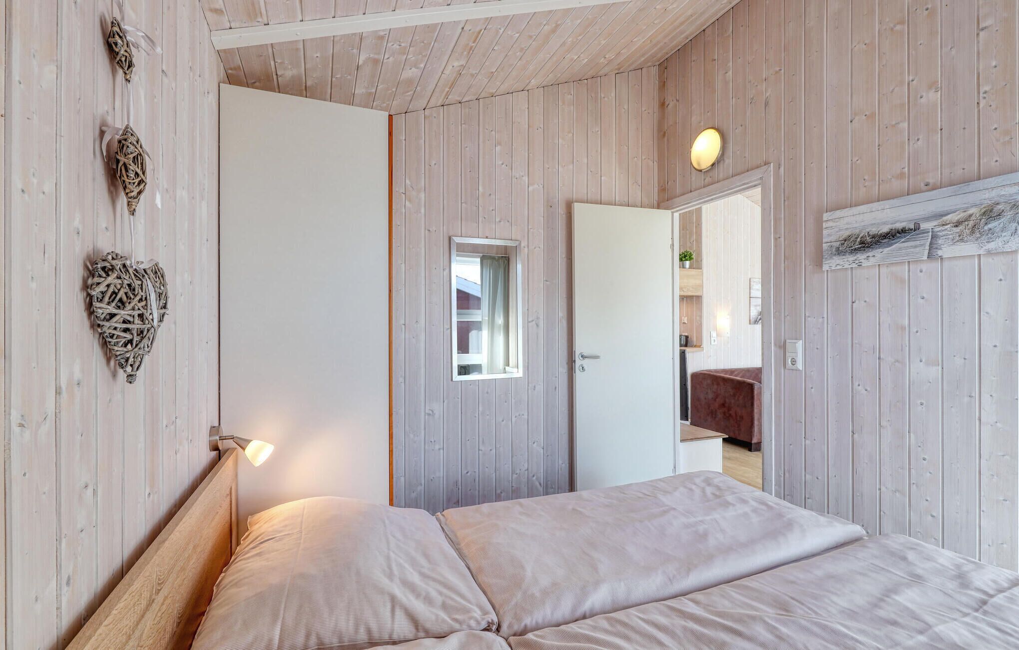 A bedroom with a wooden ceiling, a bed with a headboard, a bedside lamp, and a door leading to a bathroom.