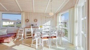 A cozy room with a wooden ceiling, a dining table with chairs, a sofa, and a view of the outside. - Beautiful home in Schönhagen with sauna (Schönhagen)