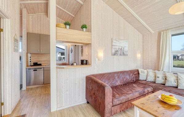 A cozy cabin interior with a wooden interior, a kitchenette, a leather sofa, and a dining area with a wooden table.