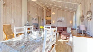 A cozy room with a dining table set for four, a sofa, a TV, and a kitchen area visible through an open door. - Beautiful home in Schönhagen with sauna (Schönhagen)