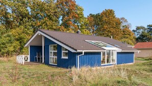 Une maison bleue avec un toit en pente et une grande fenêtre.