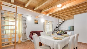 Un comedor con una mesa lista para cuatro personas, una escalera de madera y una pared de piedra.