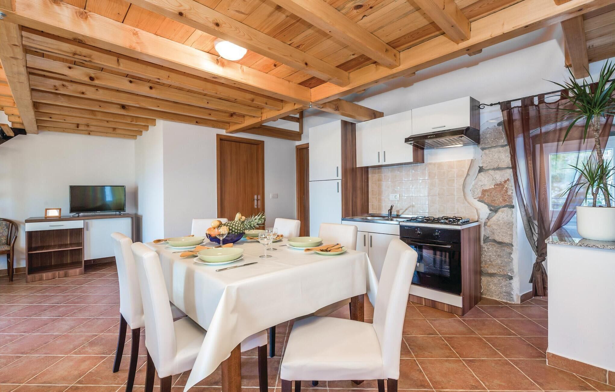 A modern kitchen with white cabinets, a stove, and a dining area with a table set for four.