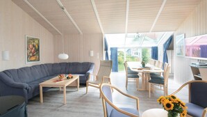 Una sala moderna con un sofá gris, una mesa de centro de madera y una zona de comedor con una mesa y sillas.