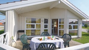 A covered outdoor seating area with a table and chairs, a tennis racket, and a bowl of fruit. - Nice home in Schönhagen with sauna (Schönhagen)