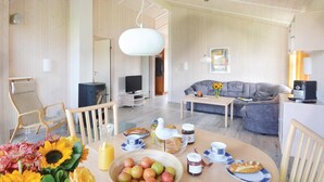 A spacious living room with a sofa, a dining table set with fruits and pastries, and a television in the background. - Nice home in Schönhagen with sauna (Schönhagen)
