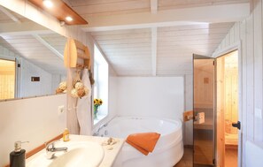 Bagno con una vasca da bagno bianca, un lavabo con specchio e una finestra con vista all'esterno.