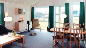 A room with a wooden table, chairs, a chessboard, a lamp, and a view of the outdoors through large windows. - Nice home in Schönhagen with sauna (Schönhagen)