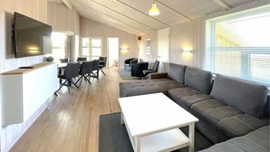 A modern living room with a sectional sofa, a white coffee table, and a dining area with chairs and a table. - Friedrichskoog-Strandpark 3 (Friedrichskoog)