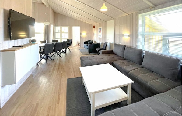 Un salon moderne avec un canapé d’angle, une table basse blanche et un coin repas comprenant des chaises et une table.