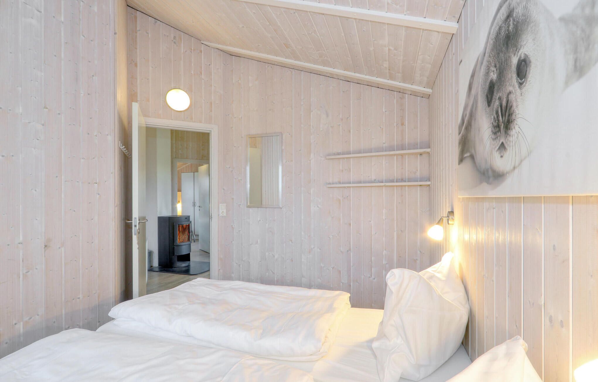 A bedroom with a bed, a wall-mounted shelf, and a door leading to another room.