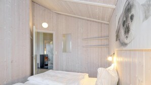 Ein Schlafzimmer mit einem Bett, einem Wandregal und einer Tür zu einem weiteren Raum.
