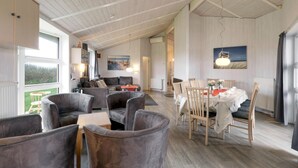 Ein geräumiges Loft mit hoher Decke, einem Essbereich mit rundem Tisch und Stühlen sowie einer gemütlichen Sitzecke mit Sofas und Sesseln.