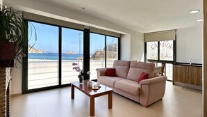 Un salon spacieux doté d’une grande fenêtre donnant sur la plage et l’océan.