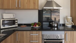 Une cuisine moderne avec des meubles en bois, une hotte en acier inoxydable, un four à micro-ondes, une cuisinière et une machine à café.
